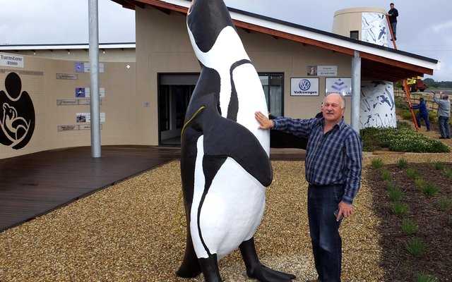 Wilfred Chivell staan by die enorme 3m Afrika Pikkewyn kort voordat dit met ‘n hyskraan op die APSS sentrum se dak geplaas is